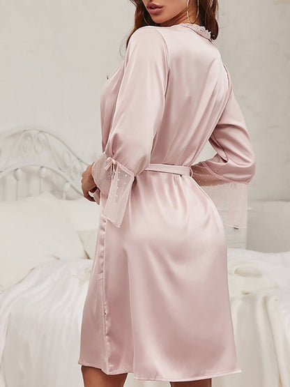 a woman in a pink robe standing in front of a bed