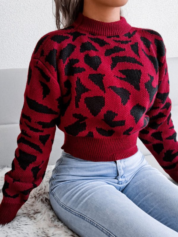 a woman sitting on a bed wearing a red and black sweater