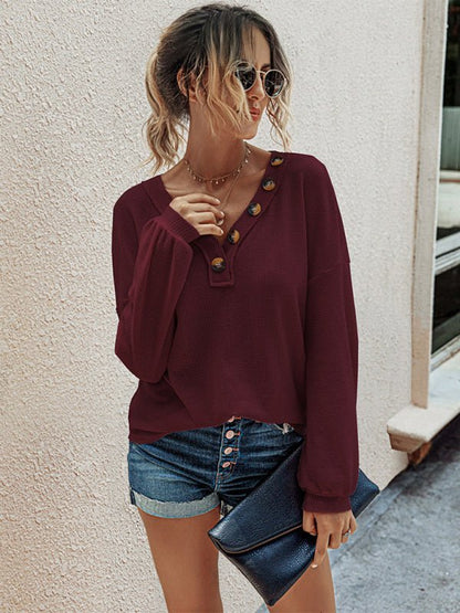 a woman wearing a burgundy top and denim shorts
