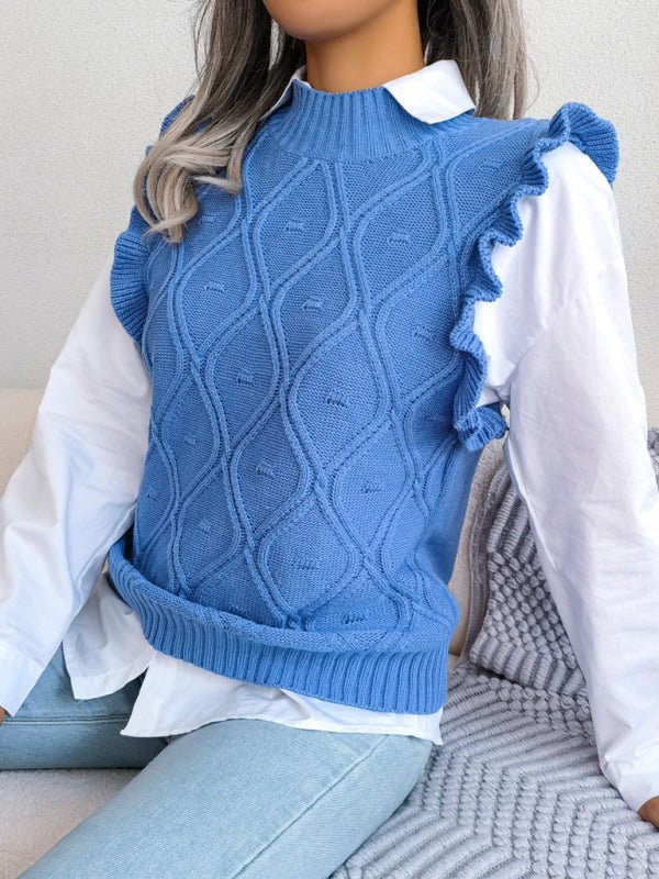 a doll sitting on a couch wearing a blue sweater