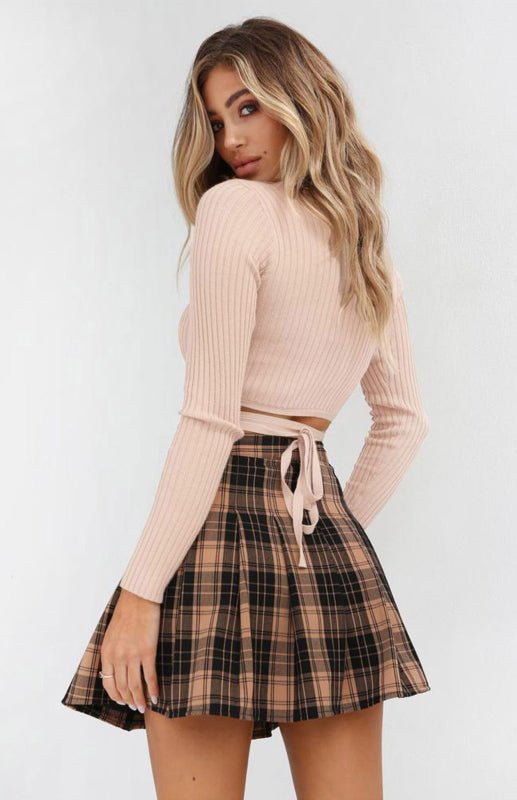 a woman wearing a pink sweater and plaid skirt