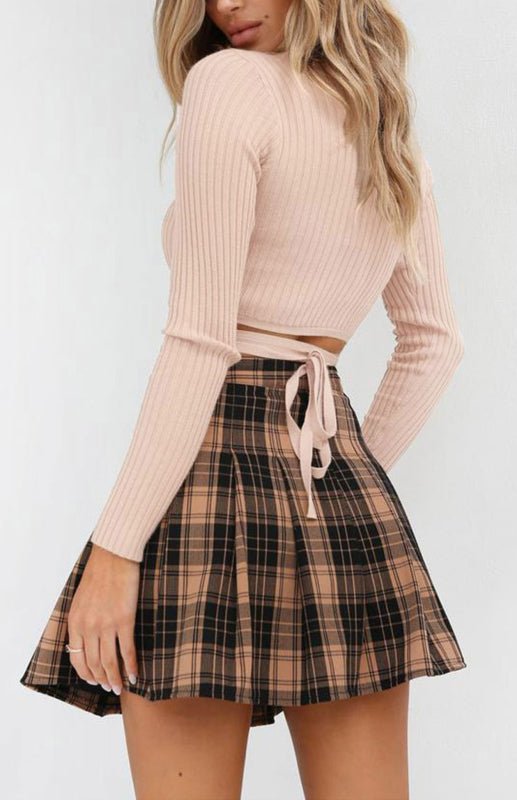 a woman in a pink sweater and plaid skirt