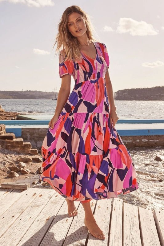 a woman in a colorful dress standing on a dock