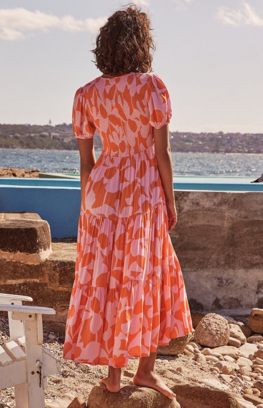 a woman in an orange and white dress standing on rocks