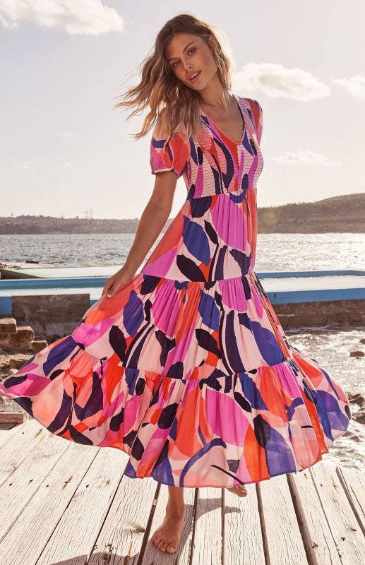 a woman standing on a dock wearing a colorful dress